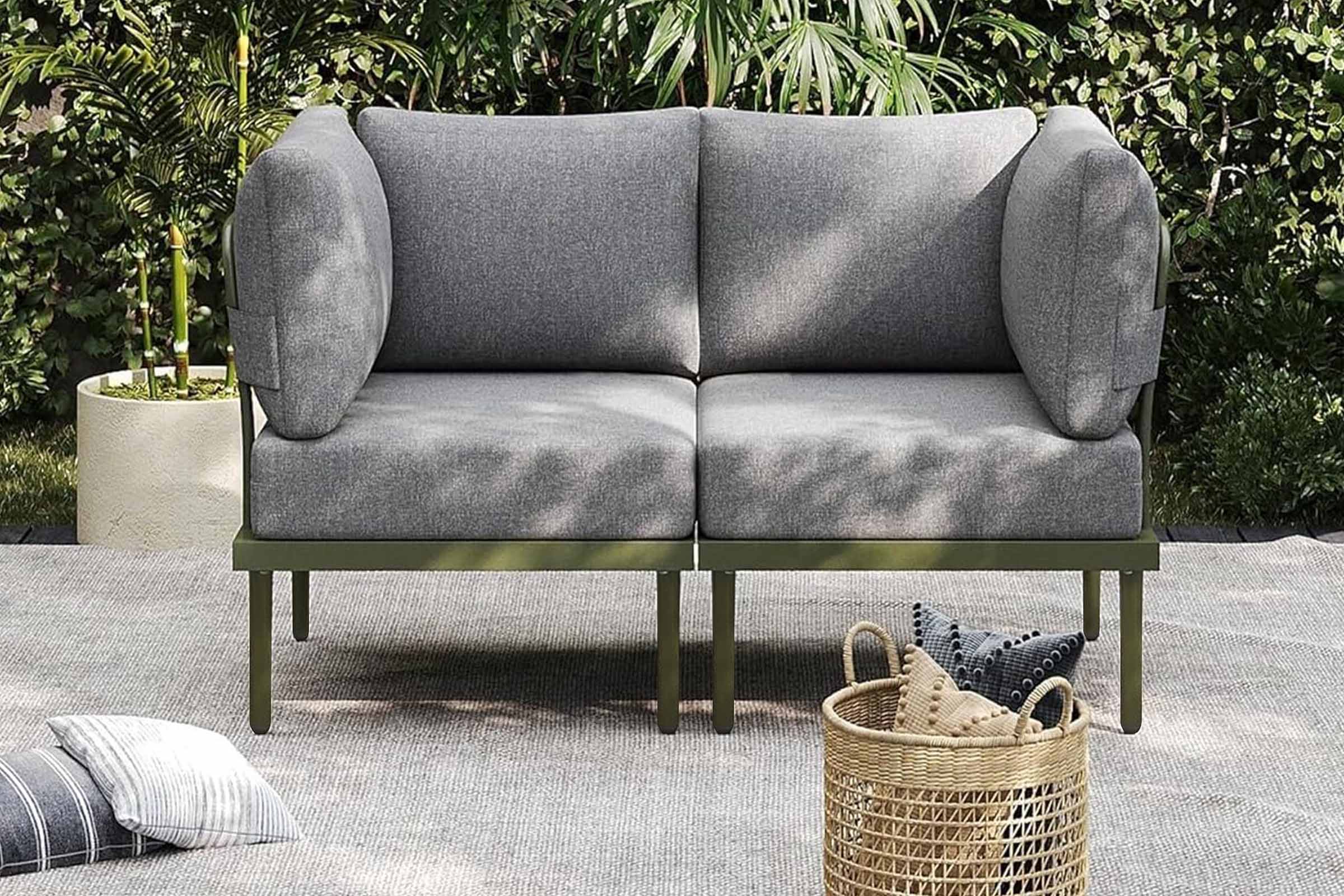 Gray outdoor sofa with green legs on a patio with plants in the background.#color_green