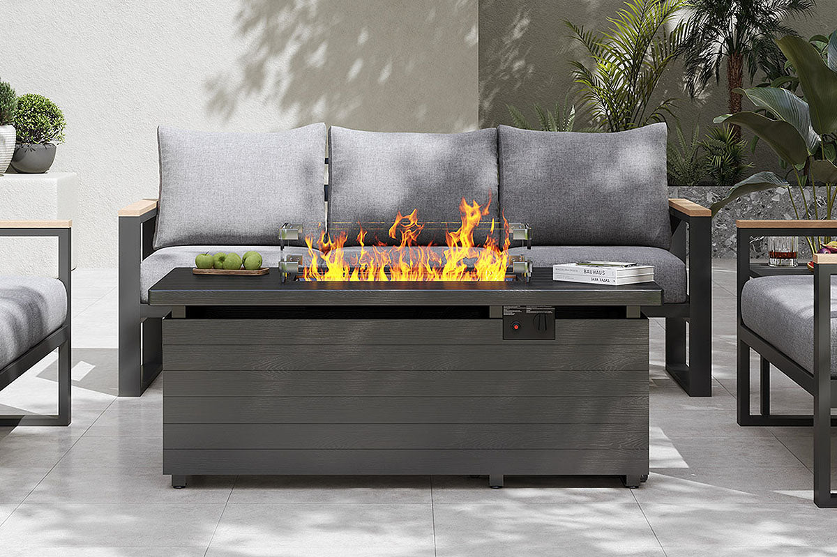 Outdoor patio setting with a fire pit table and gray sofa.#color_light gray