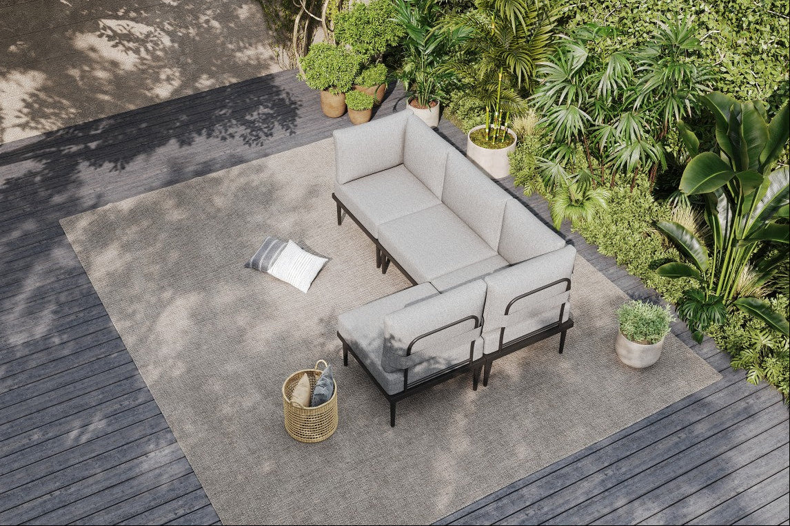 Outdoor patio with gray sectional sofa, cushions, and a small table on a concrete patio.#color_gray
