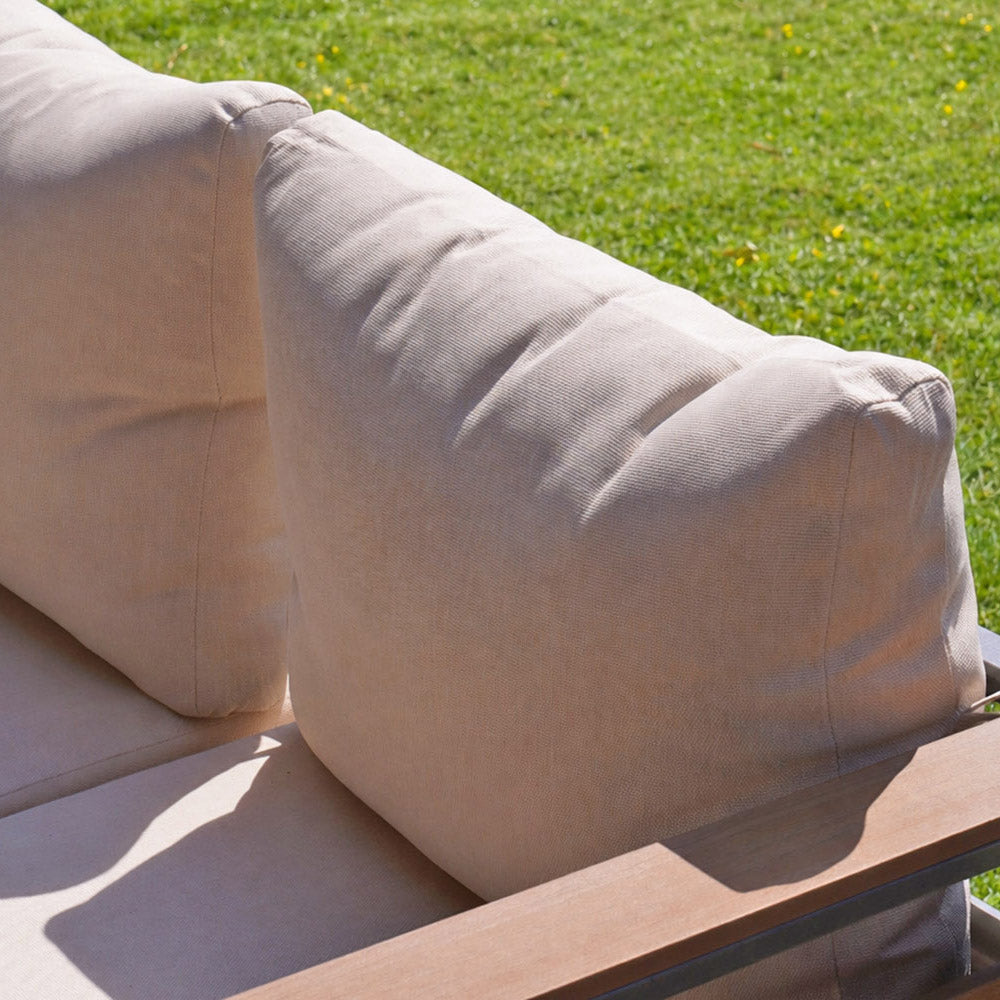 Beige cushions on a wooden grain bench with grass in the background