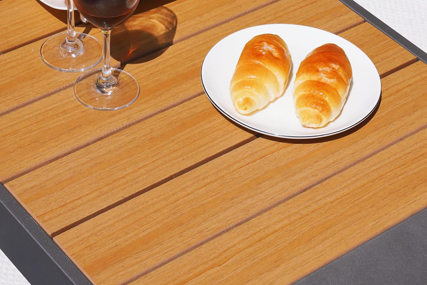 Two croissants on a white plate with a glass of red wine on a coffee table.