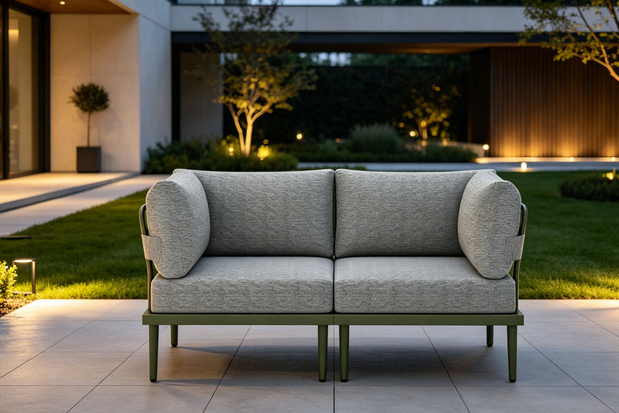 Gray outdoor sofa with green legs on a patio area with a modern house in the background.