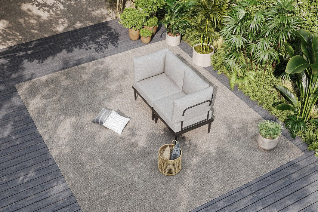Outdoor patio with gray rug, gray sofa, and potted plants.#color_gray