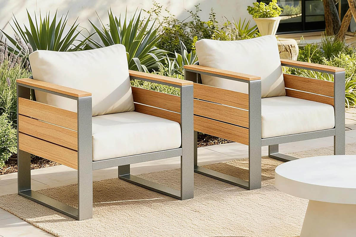 Two wooden finish chairs with white cushions on a patio with plants in the background.#color_beige