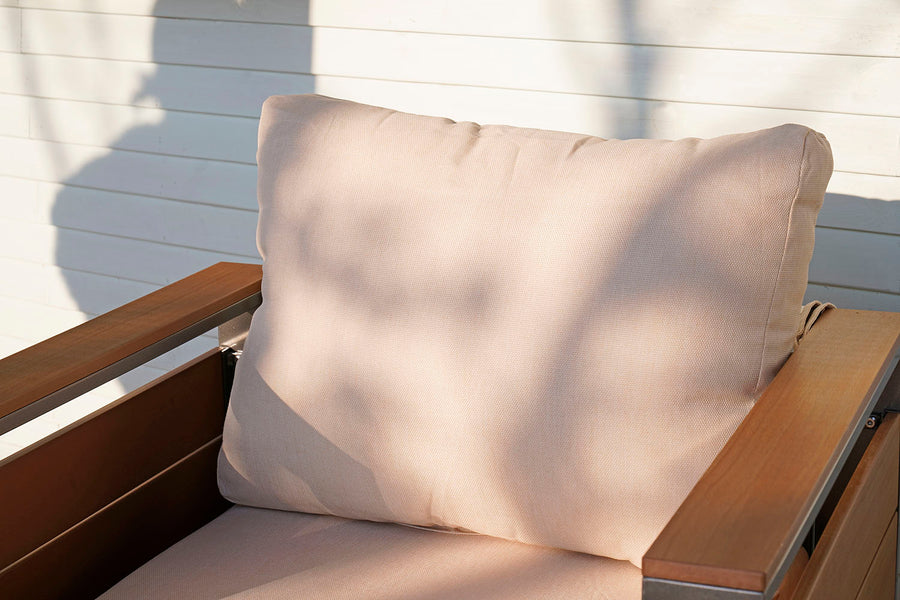 Beige cushion on a wooden finish chair against a light-colored wall