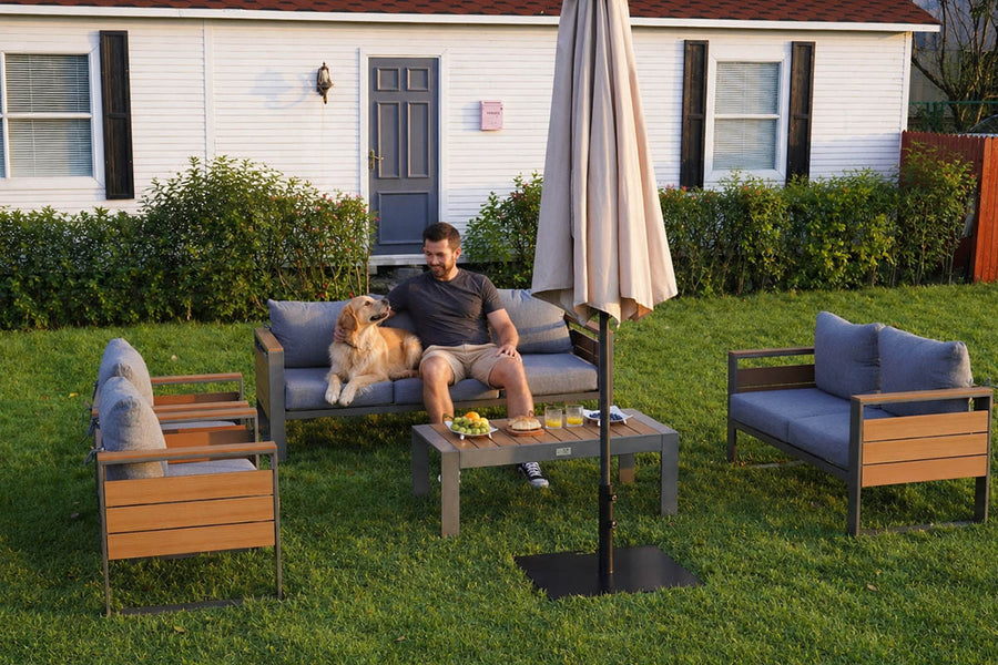 Man sitting on a patio set with a dog in a backyard