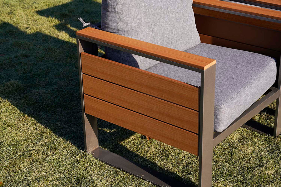 Chair with wooden finish armrest and gray cushion on grass