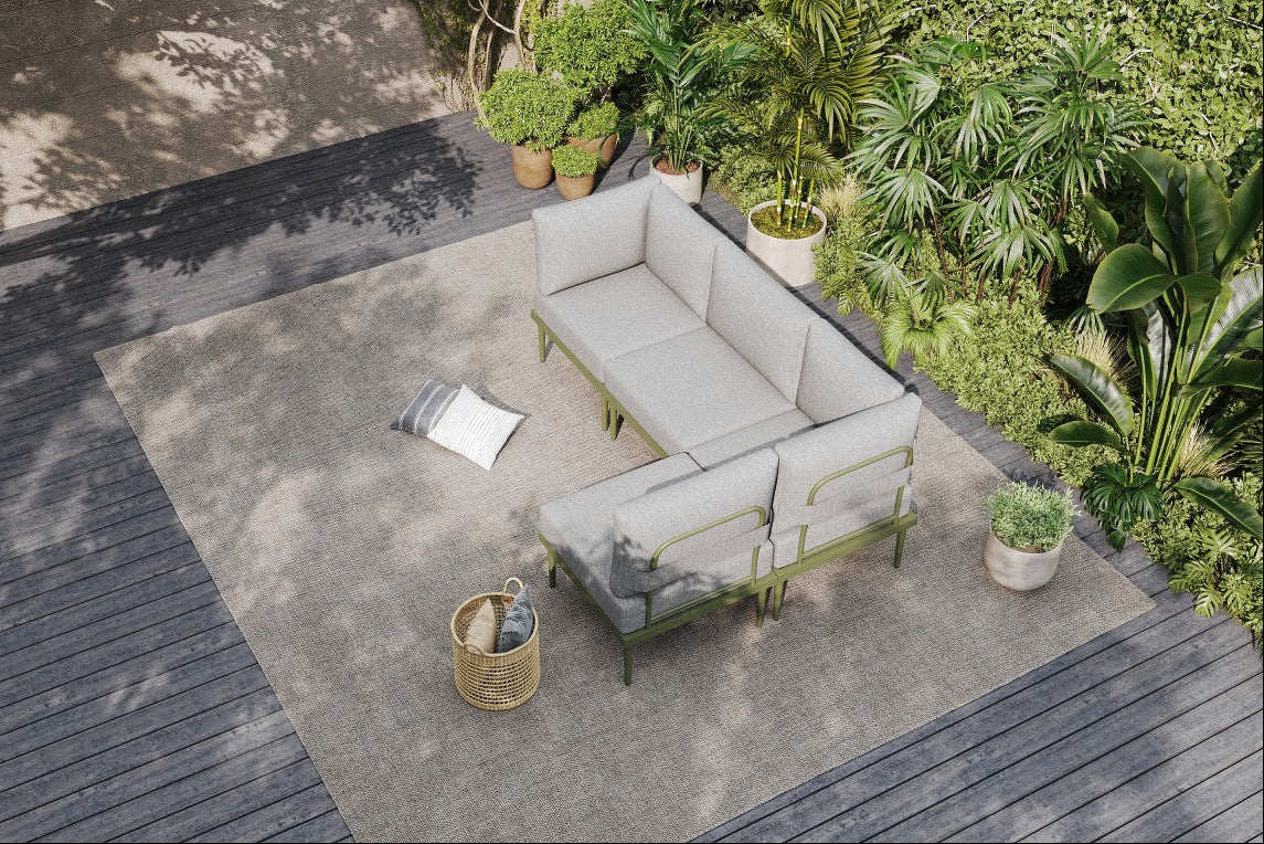 Outdoor patio with gray sectional sofa, cushions, and a woven basket on a concrete floor.#color_green