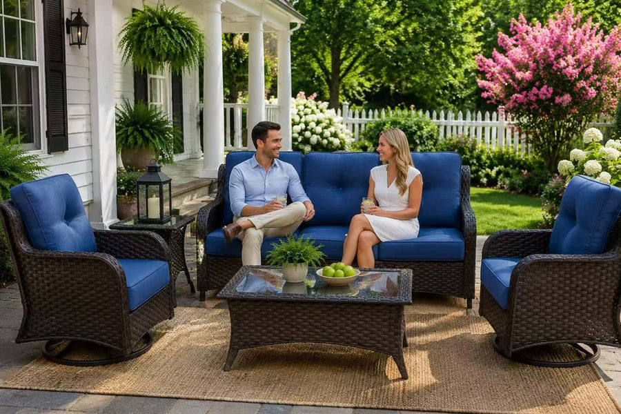 Man and woman sitting on a blue outdoor sofa set with a table in a garden setting.