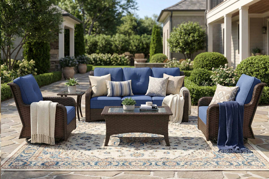 Outdoor patio set with blue sofa, chairs, and coffee table on a stone patio.