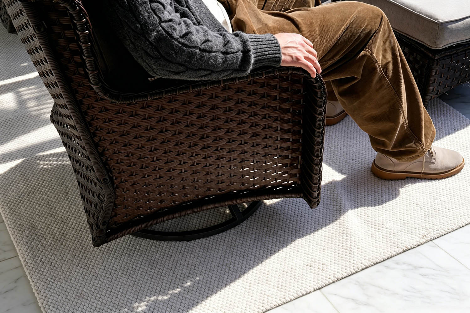 Person sitting on a wicker chair on a patio.#color_gray