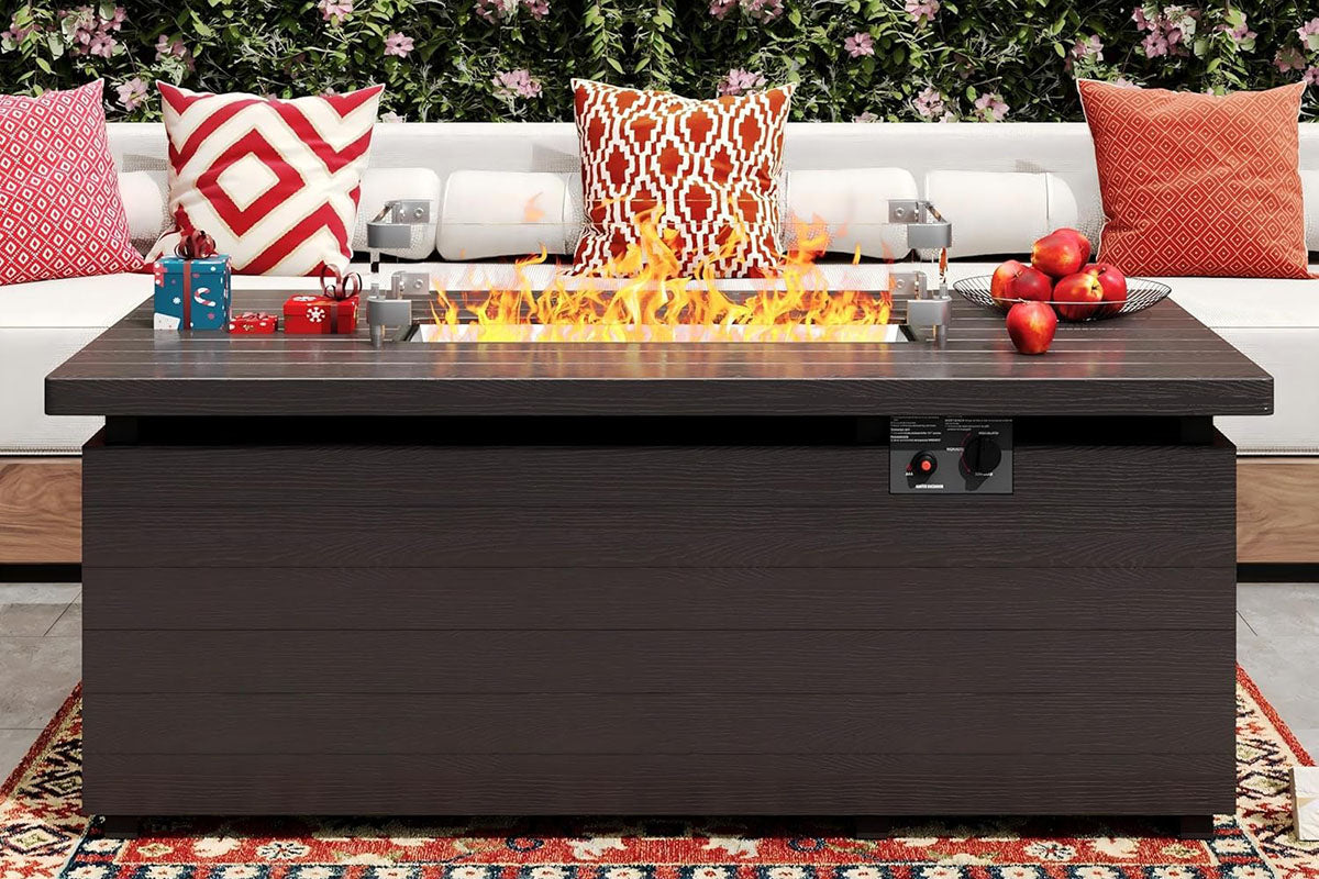 Outdoor fire pit table with flames, surrounded by decorative pillows and items on a patio.#color_brown