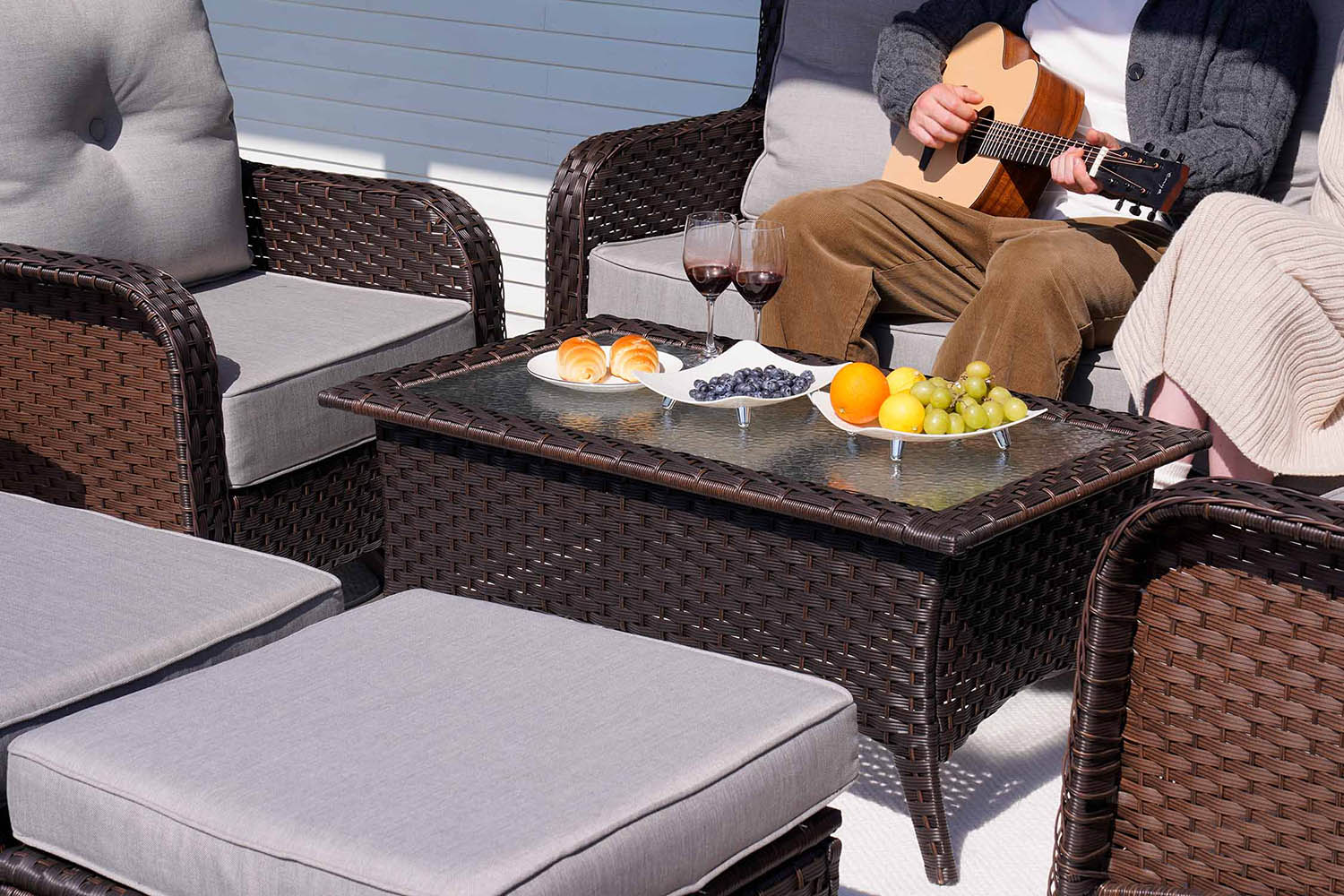 Outdoor patio furniture set with a coffee table, chairs, and a person playing guitar.#color_gray