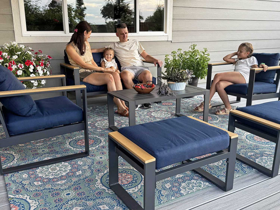 Family sitting on outdoor furniture set with blue cushions on a patio.
