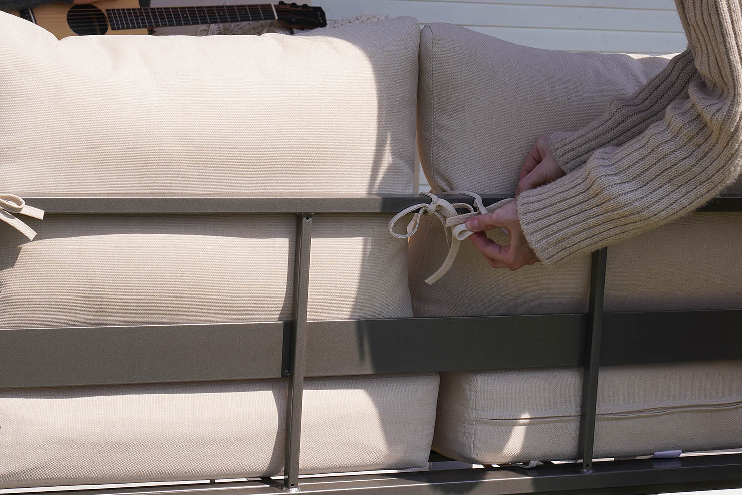 Person adjusting beige cushions on a loveseat.#color_beige