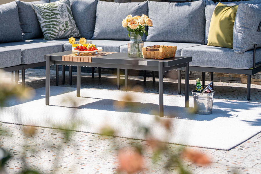 Outdoor patio setting with a sectional sofa, coffee table, and decorative items.